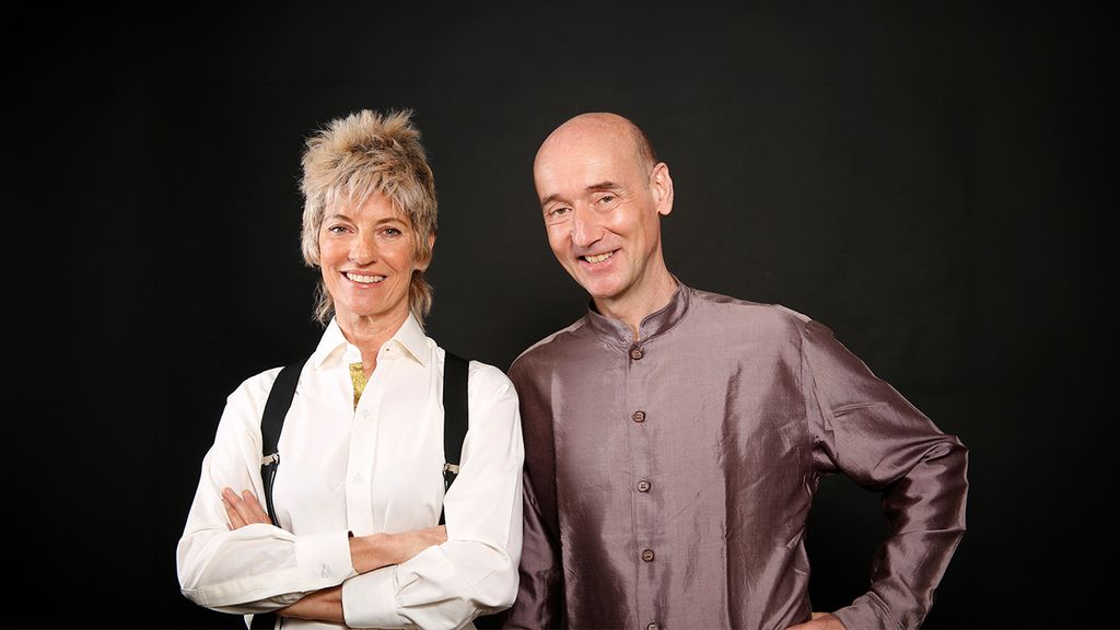 Ein Mann und eine Frau lächend vor einem schwarzen Hintergrund