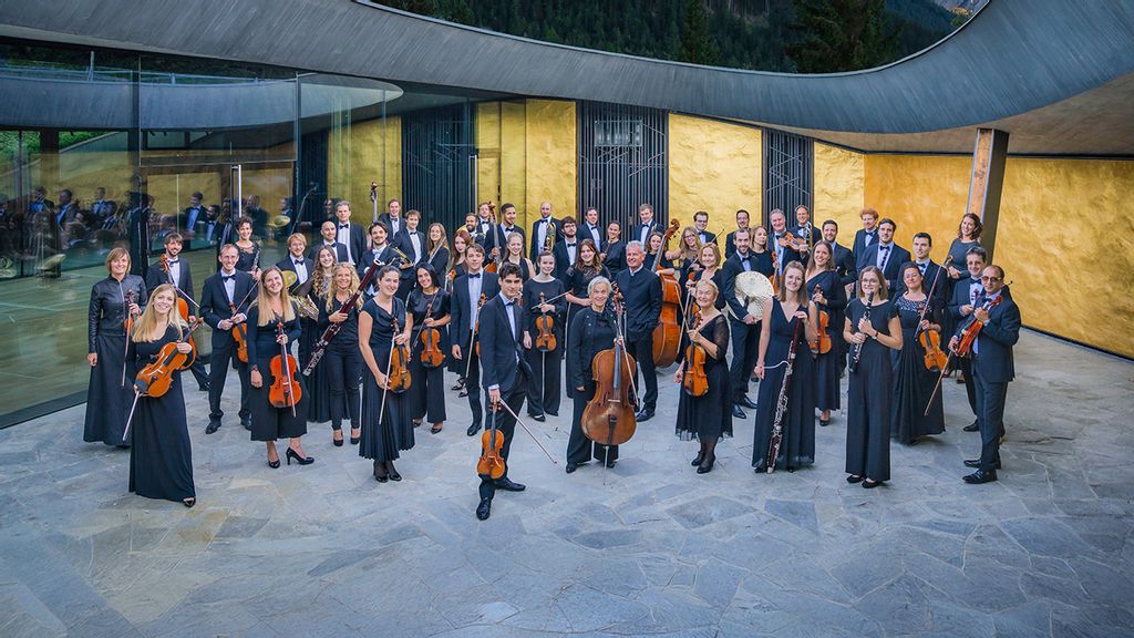 Orchestergruppe in eleganter Kleidung mit Streichinstrumenten vor modernem Gebäude