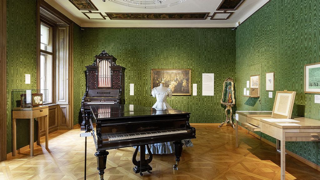 Innenraum der Johann Strauß Wohnung mit grünen Wänden und einem schwarzen Flügel Klavier