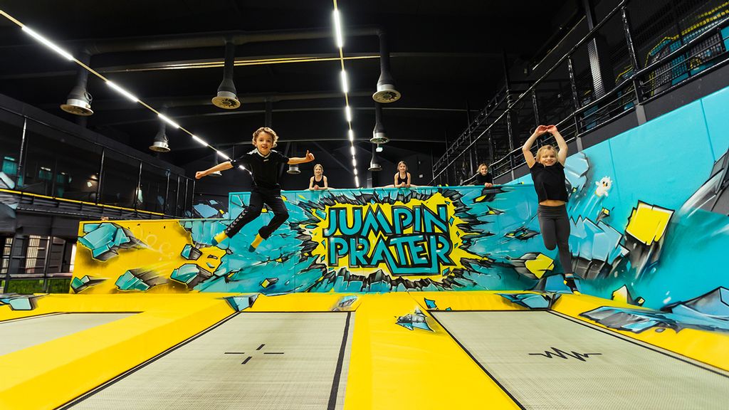 ZweiKinder springen auf Trampolinen in einer Halle
