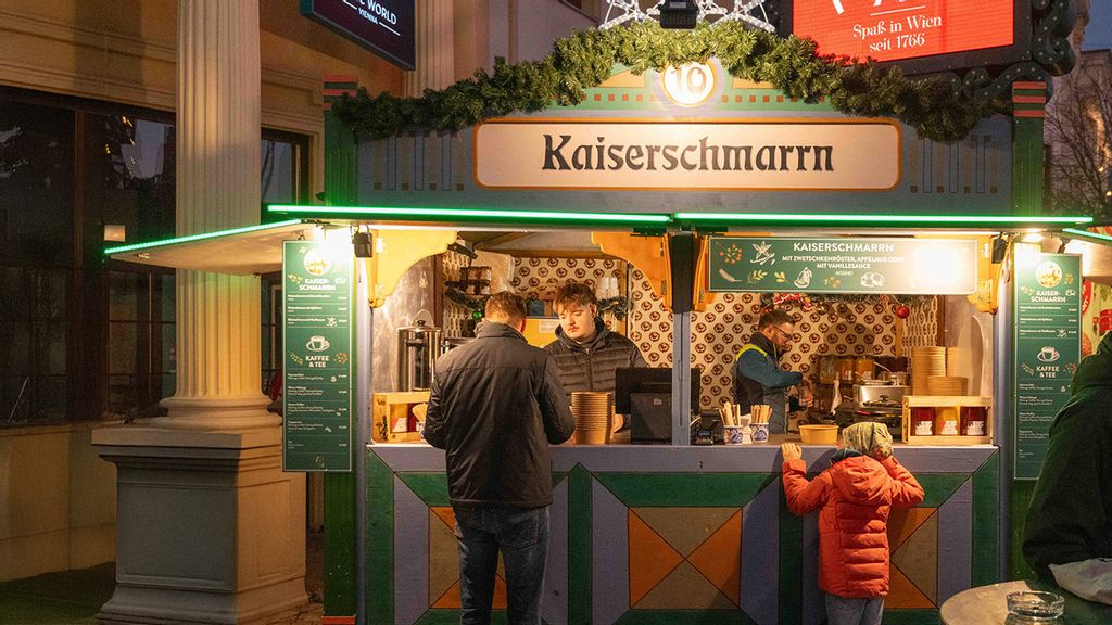 Zwei Verkäufer und weitere Personen am Wintermarkt vor bzw. in einer Hütte