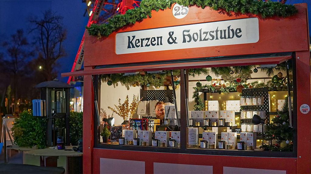 Weihnachtsmarkt-Stand bei Nacht mit Verkäufer hinter dem Tresen.