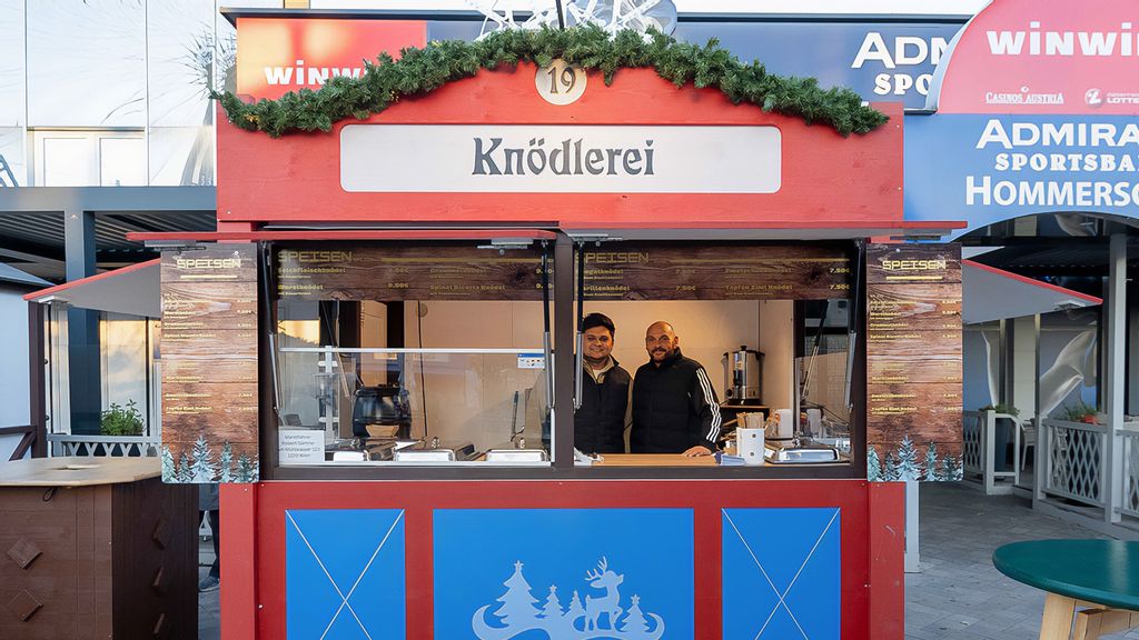 Weihnachtsmarkt-Hütte mit zwei Verkäufern.