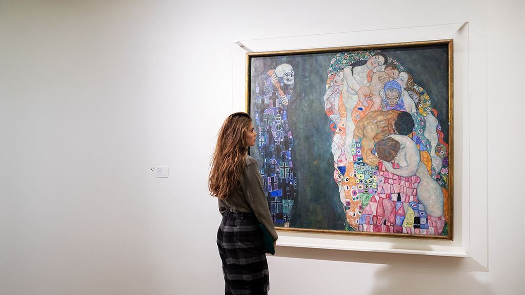 Ene Frau betrachtet ein Gemälde von Klimt im Museum