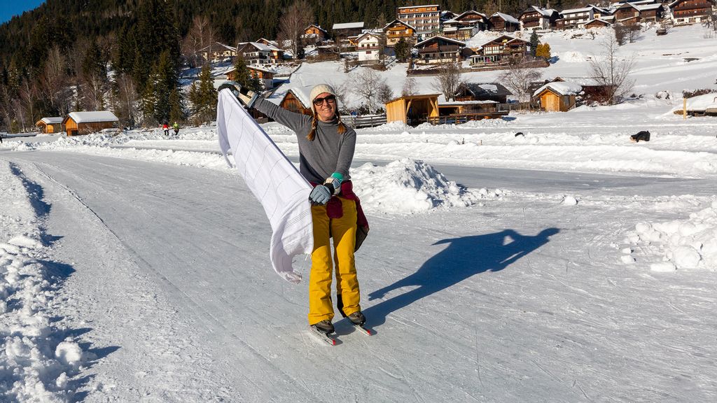 Frau steht auf einer Schneefahrbahn und präsentiert ein weißes Tuch