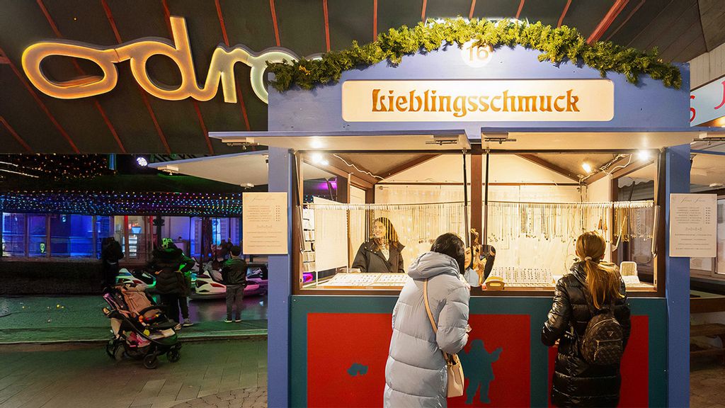 Weihnachtsmarkt-Hütte mit Verkäuferin, umgeben von Personen