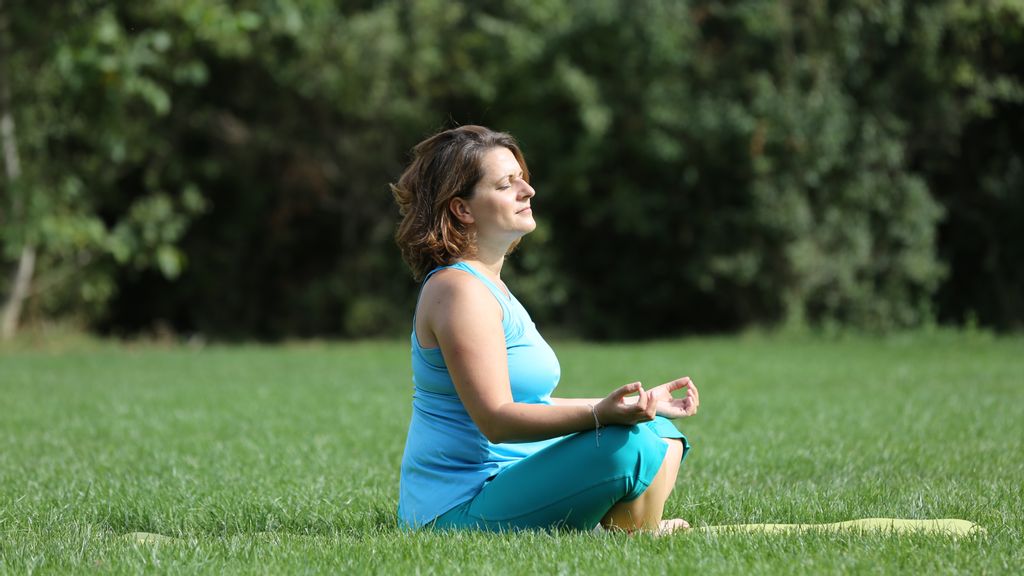 Outdoor Yoga - Meditierende Frau auf einer Wiese