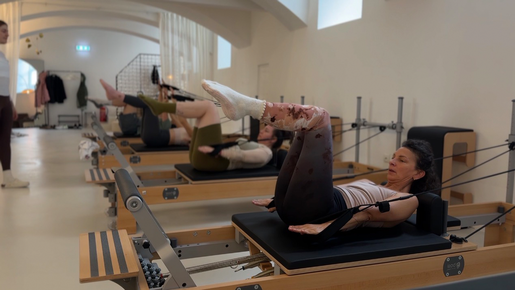 Gruppe an Frauen in einer Gruppen Reformer-Pilates Stunde