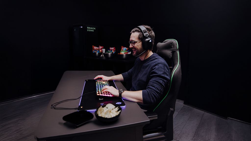 Mann spielt auf einer LAN-Party mit beleuchteter Tastatur
