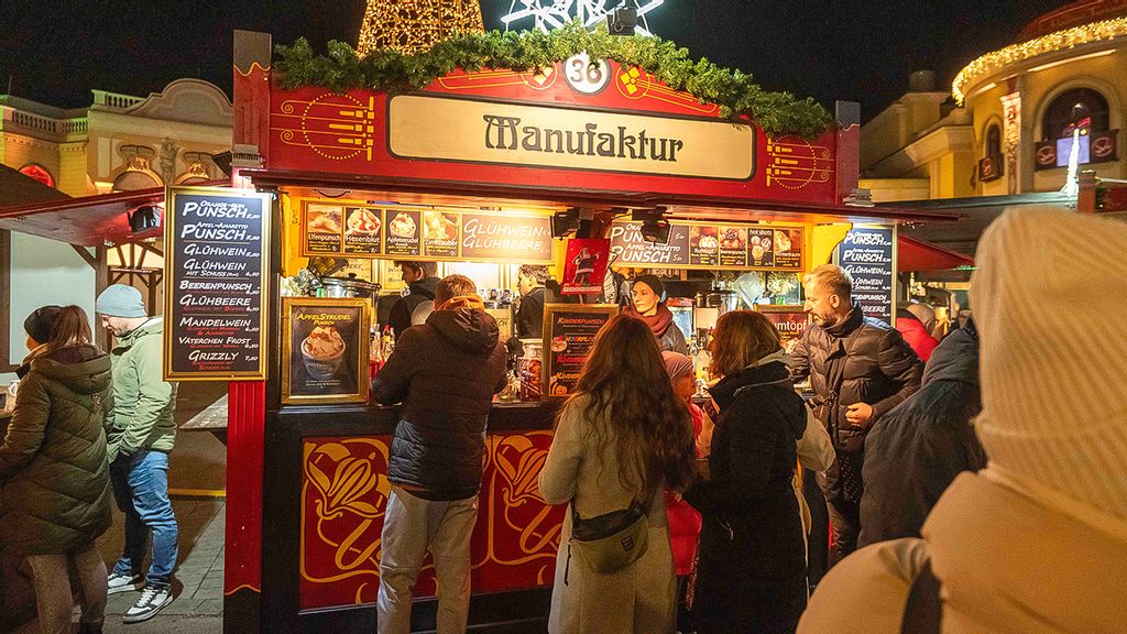 Mehrere Mitarbeiter*innen und Personen am Wintermarkt vor bzw. in einer Hütte