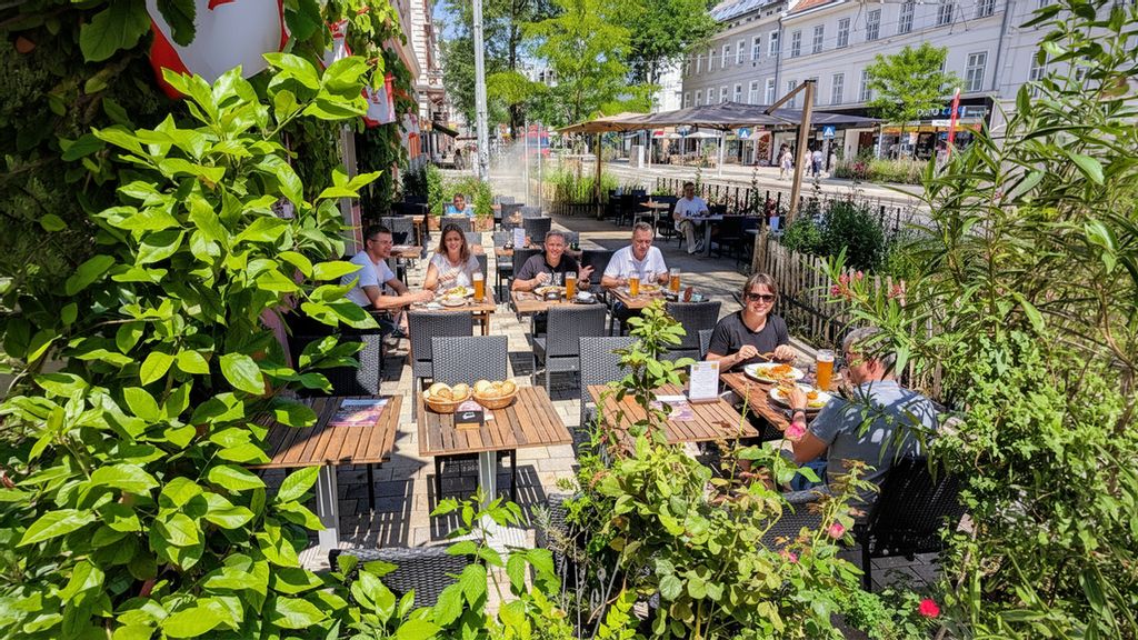 Gäste eines Restaurants sitzen in einem Gastgarten