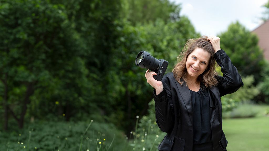 Fotografin mit Kamera in der Hand auf einer Wiese