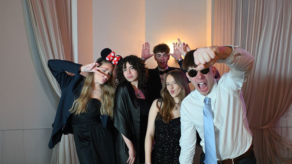 Gruppe junger Personen posieren mit lustigen Accessoires vor einer Fotobox