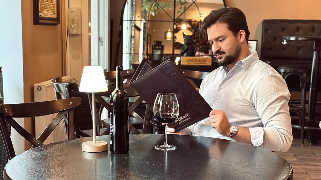 © MOZAIK Café & Restaurant Ein Mann sitzt in einem Restaurant und blickt in die Speisekarte