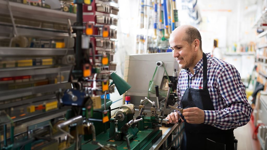 Ein Mann fertigt einen Schlüssel mit einer Maschine an 