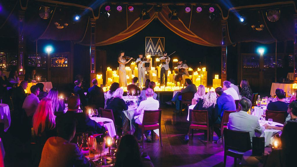 Ein Streichquartett spielt bei Kerzenschein auf der Bühne vor einem Publikum 