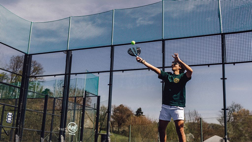 Ein Mann retourniert den Ball beim Padeltennisspielen im Freien