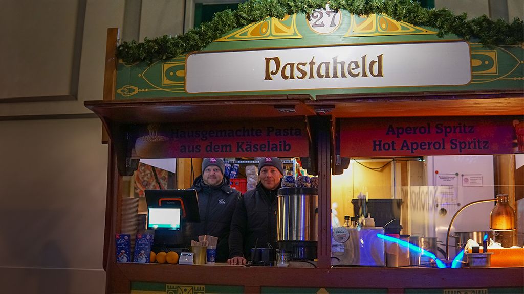 Weihnachtsmarkt-Stand bei Nacht mit Verkäufern hinter dem Tresen.
