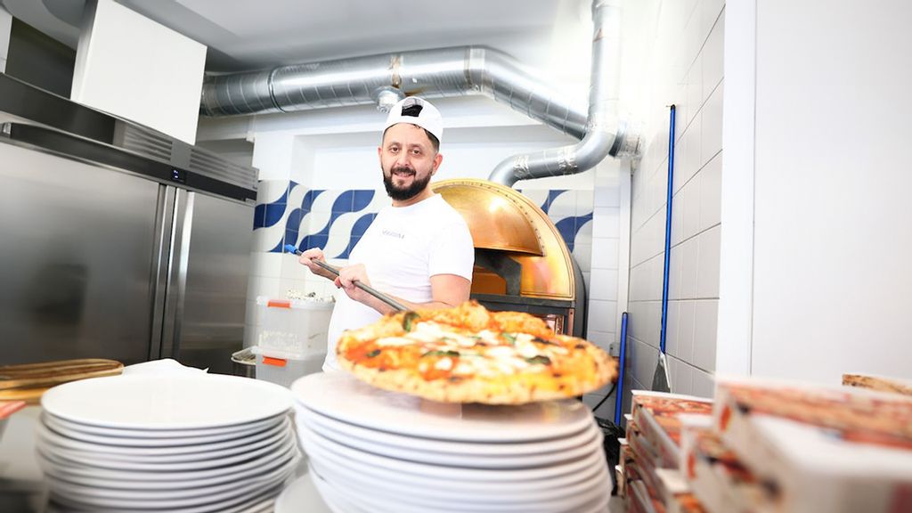 Pizzabäcker platziert eine Pizza auf einem Teller