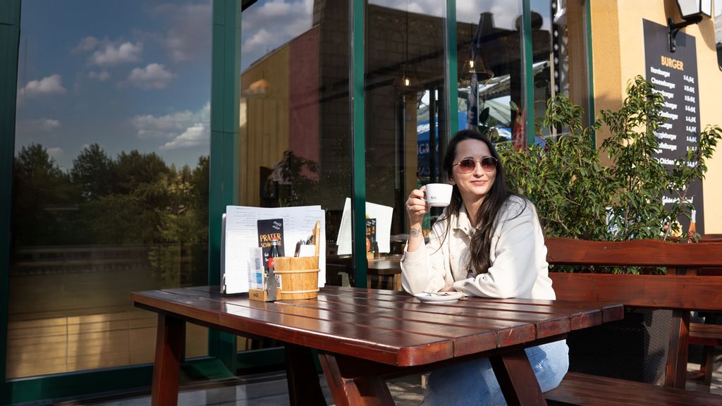 Eine Frau genießt einen Kaffee im Gastgarten von der Praterschwemme