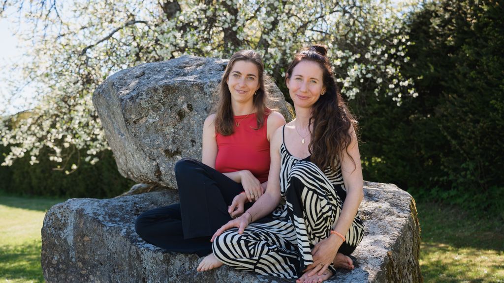 Zwei Frauen sitzen im freien auf einem Felsen zusammen