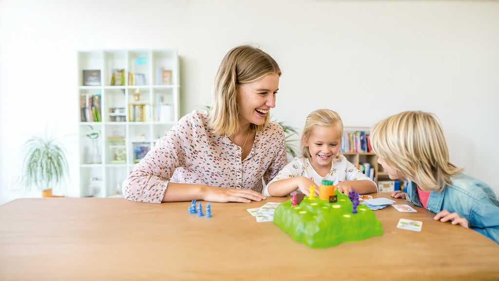 Eine Frau und zwei Kinder spielen gemeinsam ein Gesellschaftspiel