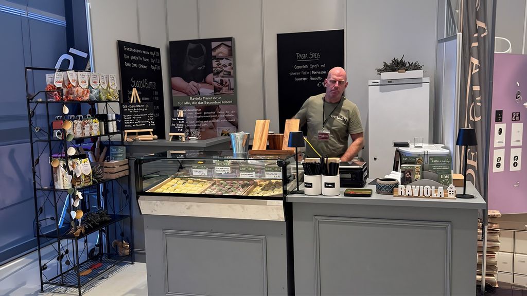 Ein Pasta-Verkäufer steht hinter einer Theke und blickt nach unten