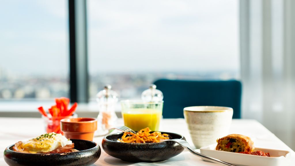 Verschiedene Frühstücksprodukte auf einem gedeckten Tisch, im Hintergrund sieht man die Stadt Wien
