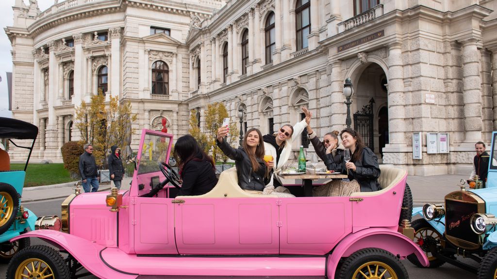 Mehrere Personen sitzen in einem Oldtimer und nehmen bei einer Ring Tour teil