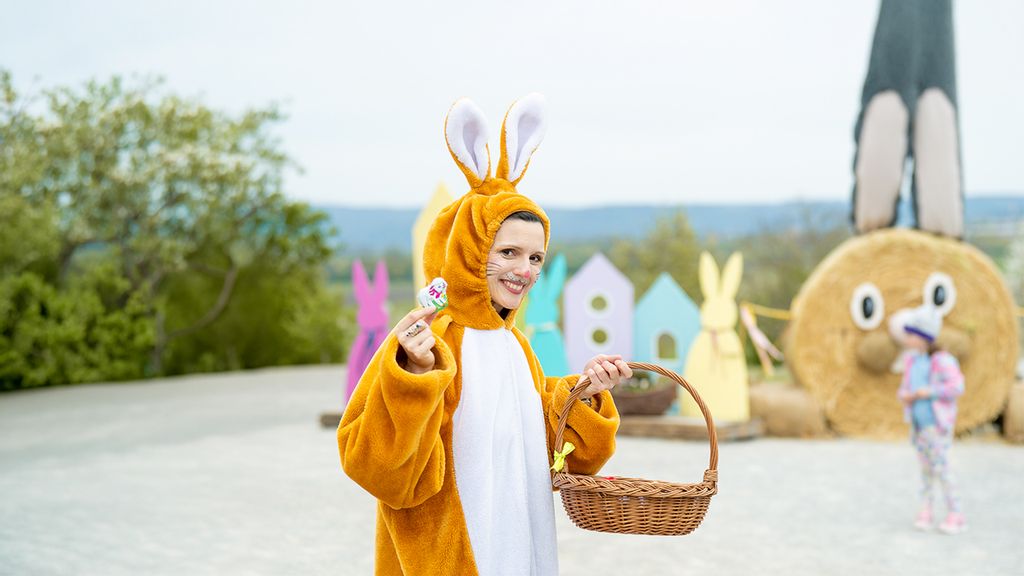 Frau in einem Osterhasenkostüm mit einem Osterkorb in der Hand