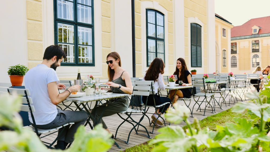 Eine Gruppe an Personen beim Essen im Schloss-Restaurant im Freien