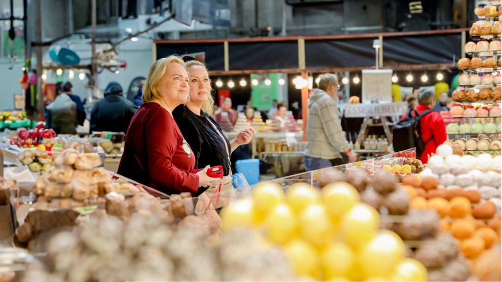 Zwei Frauen stehen vor einem Stand, der viele Pralinen und Schokolade anbietet