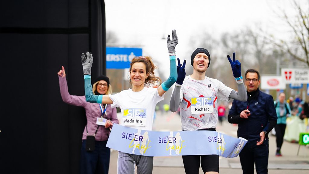 Eine Frau und ein Mann rennen durchs Ziel beim Sie+Er Lauf