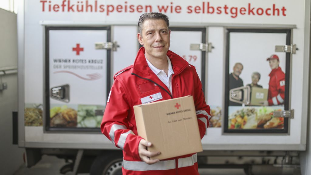 Ein Mann liefert ein Paket vom Roten Kreuz aus