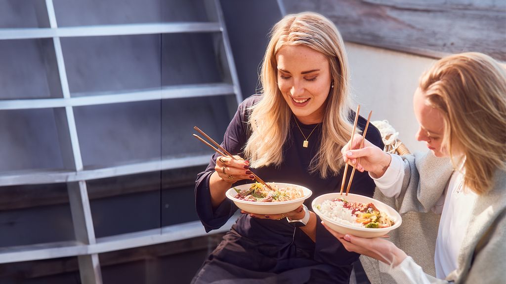 Zwei Frauen essen Bowls mit Stäbchen