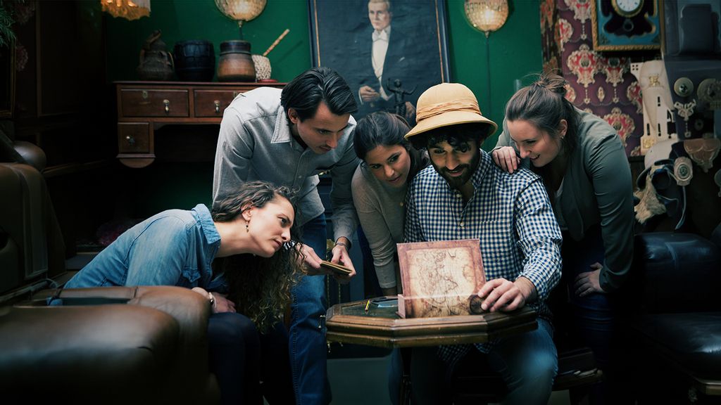 Gruppe an Personen beim Lösen eines Rätsels in einem Escape Room