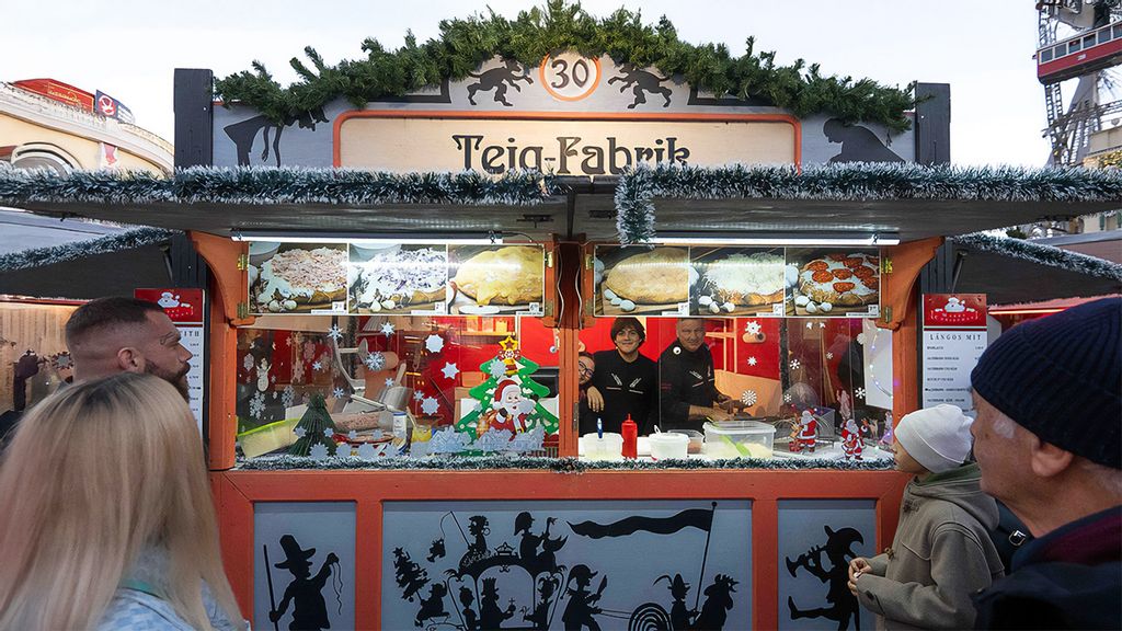 Mitarbeiter*innen in der Hütte und mehrere Personen vor bzw. neben der Hütte am Wintermarkt