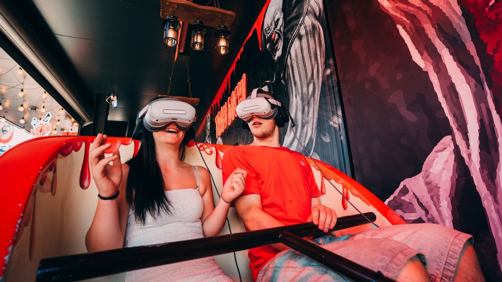 Zwei Personen sitzen in einem Fahrgeschäft mit einer VR-Brille