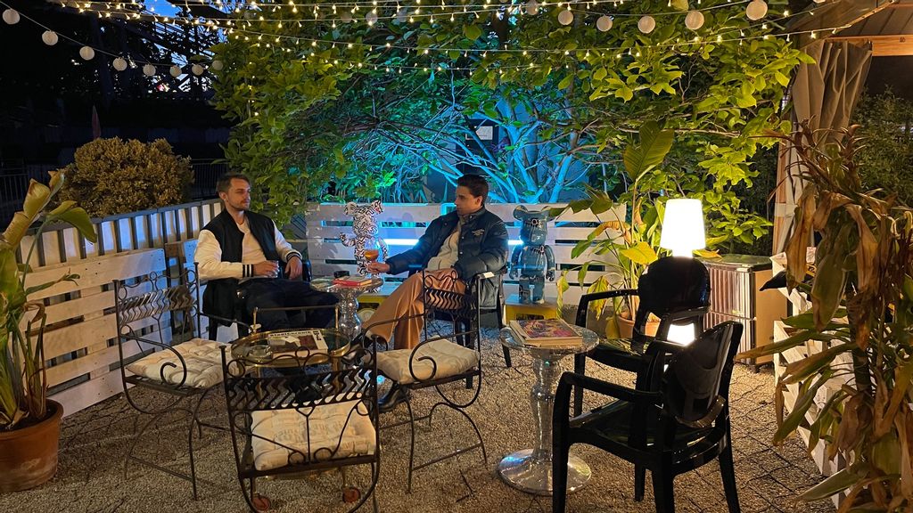 Zwei Personen sitzen im Gastgarten einer Cocktailbar zusammen