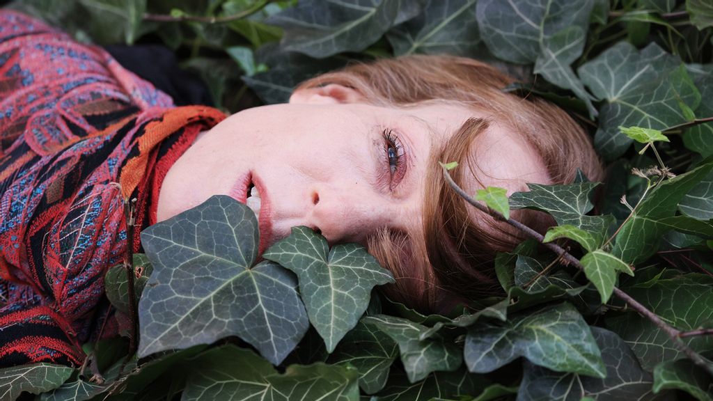 Frau liegt in einem Beet von grünen Blättern
