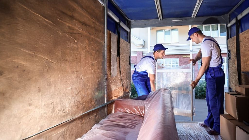 Zwei Männer laden verpackte Möbel aus einem LKW