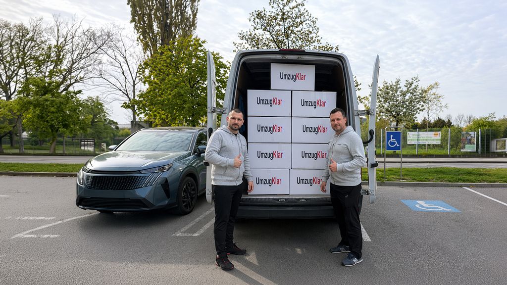 Zwei Männer einer Umzugsfirma stehen vor einem Transporter