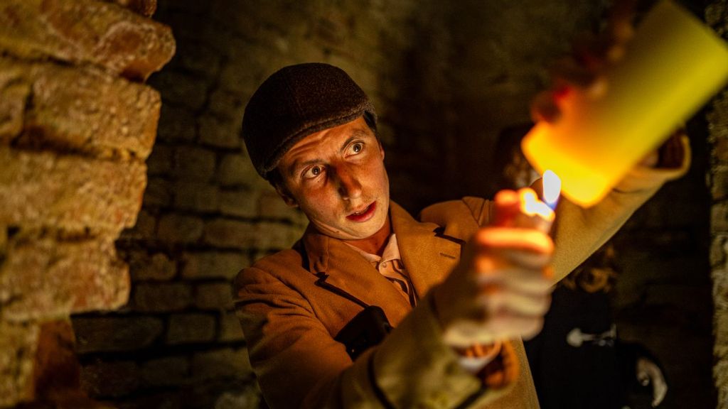 Mann mit Kerze in historischem Kellergewölbe bei einer Führung