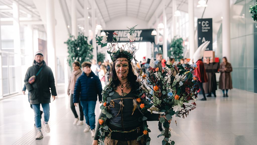 Frau in einem fantasievollen Pflanzenkostüm mit Blumen und Zweigen bei einer Veranstaltung