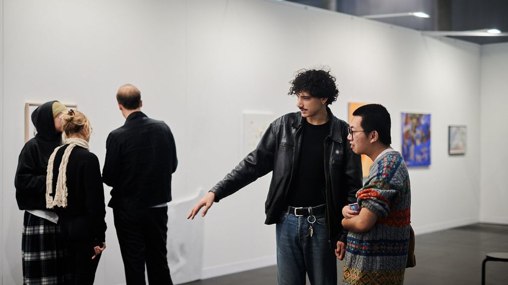 Besucher*innen betrachten und besprechen Kunstwerke in einer modernen Ausstellung.