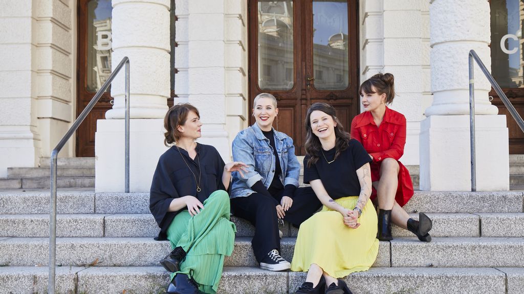 Vier Frauen sitzen vor einem Museum auf der Treppe