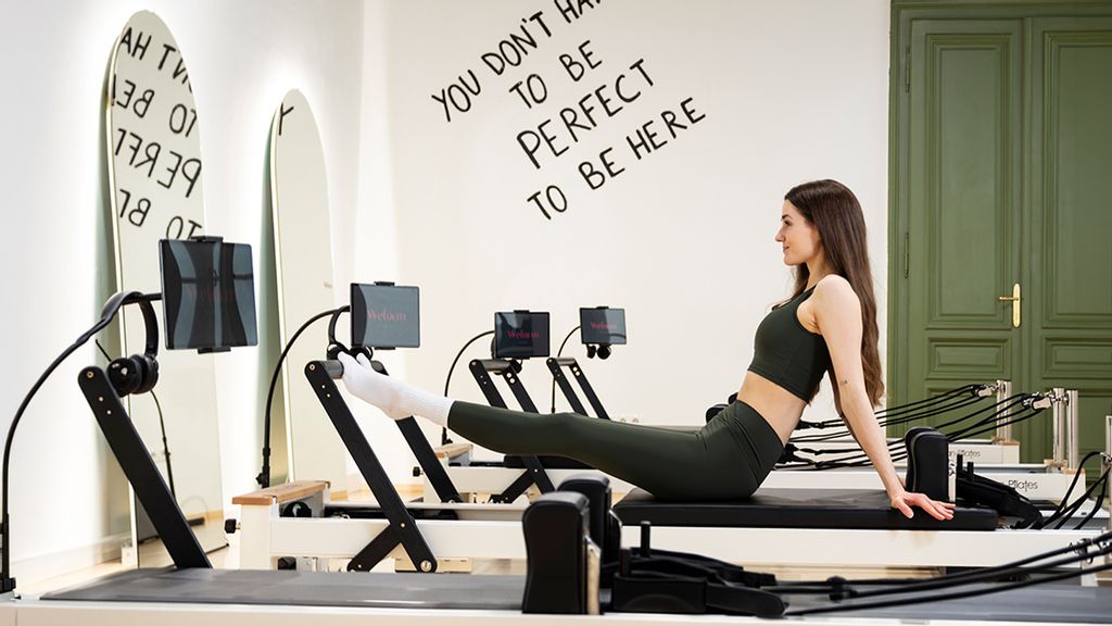 Frau auf einem Reformer Gerät bei einer Video Pilates Stunde