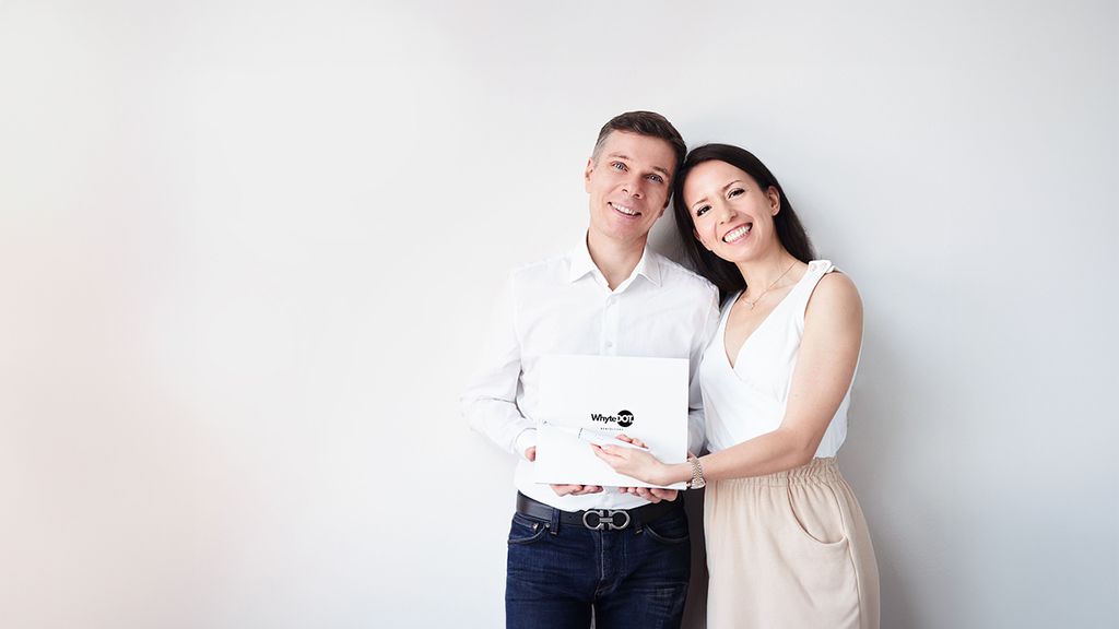 Eine Frau und ein Mann halten ein Produkt in Händen und lächeln