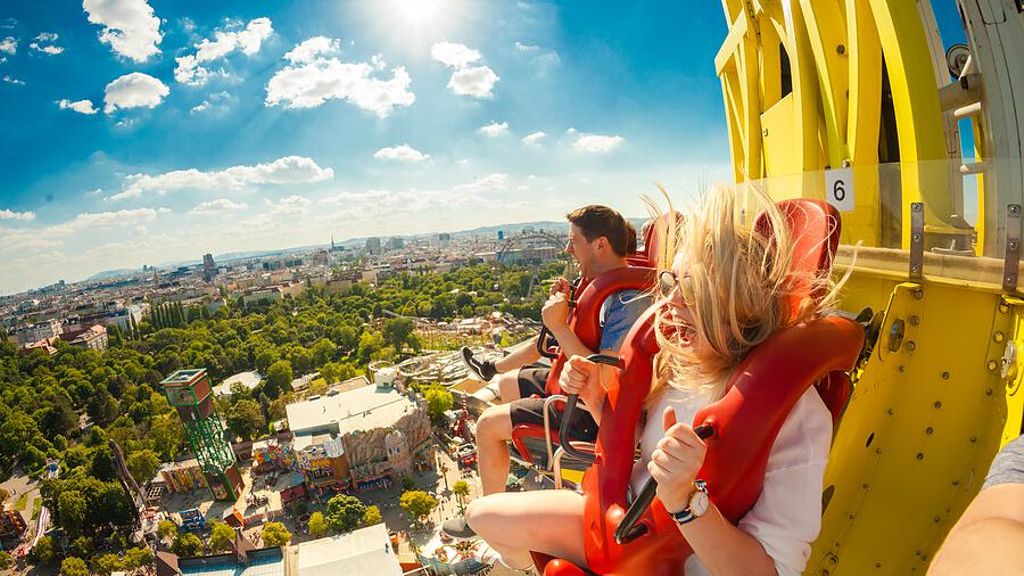 Zwei Personen sitzen im Freifallturm und im Hintergrund der Prater als Aussicht