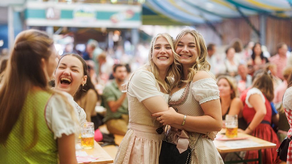 Zwei junge Frauen im Dirndl umarmen sich auf die Wiener Kaiser Wiesn